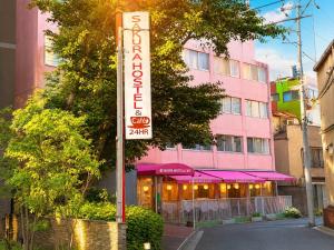 a hotel sign in front of a pink building at Sakura Hostel Asakusa in Tokyo