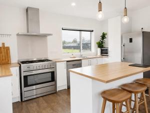 a kitchen with a stove and a counter with stools at The Burnby in Te Anau +3 photos