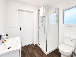 a white bathroom with a shower and a toilet at The Burnby in Te Anau