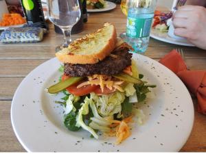 a white plate with a sandwich and a salad at Alte Kalkoefen Lodge in Simplon