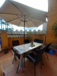 a table and chairs with an umbrella on a patio at Relax Pinares in Lepe