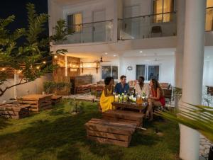 a group of people sitting around a table in a yard at The Hills in Accra