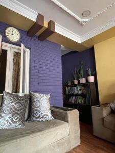 a living room with a couch and a clock on the wall at Patan Nest in Pātan