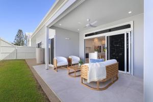 a patio with wicker chairs and a table at Basalt Beach House in Bargara