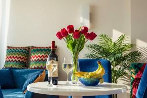 a table with a bottle of wine and a vase of red tulips at Batumi Sky Palace in Batumi