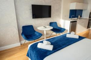 a room with a bed and two blue chairs and a table at Batumi Sky Palace in Batumi