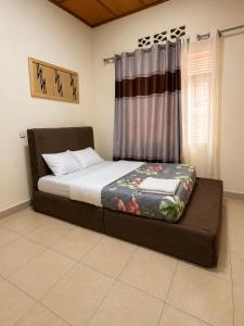 a bed sitting in a room with a window at The Gathering in Kigali