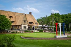 a building with a thatched roof with a golf course at Grand Slam in Le Vaudreuil