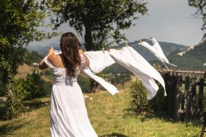 a woman in a white dress hanging clothes on a clothes line at Fairytale cottage Francka in Gorica pri Slivnici