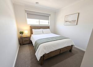 a white bedroom with a bed and a window at St Germain House, Clyde North in Clyde North