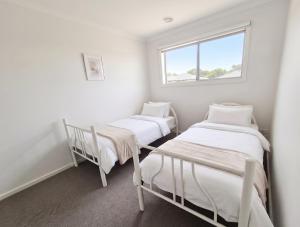 two twin beds in a room with a window at St Germain House, Clyde North in Clyde North +1 photo
