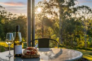 a table with a bottle of wine and a glass at Dundalli Lodge in Conondale +15 photos