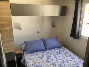 a bed with two blue pillows in a room at Camping La Aventura Playa in Daimuz