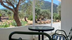 a table and chairs in front of a window with a tree at Firogia Olive Grove Hideaway in Sifnos