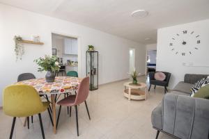 a living room with a table and chairs and a clock at הדירה של אייזיק - דירה מהממת במצפה רמון עם נוף מדהים in Mitzpe Ramon