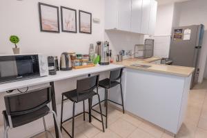 a kitchen with a counter with stools and a microwave at הדירה של אייזיק - דירה מהממת במצפה רמון עם נוף מדהים in Mitzpe Ramon