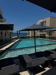 a swimming pool with umbrellas and chairs next to a building at Avanel Signature in Sarandë