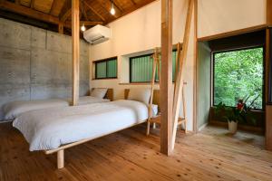 two beds in a room with wood floors and windows at Beppu TOJIHAUS 002 Hilltop Sea View 8min walk to Hells of Beppu in Beppu