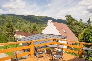 a deck with chairs and a roof with mountains in the background at Biesy2 in Wetlina