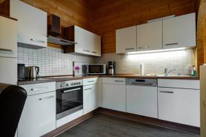 a kitchen with white cabinets and white appliances at Waldsiedlung - Haus 10 in Großkoschen