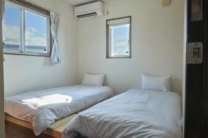 two beds in a room with two windows at 甘口派Stay in Tsurumakida