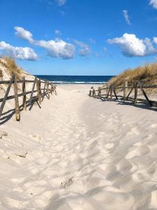 a wooden fence on a sandy beach near the ocean at Pokoje na Brzozowej 2 in Białogóra