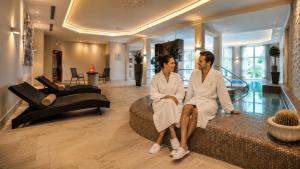 a man and woman sitting on a couch in a living room at Kurhotel Grüttner mit eigenem Sole Thermal Schwimmbad 32 Grad und Saunalandschaft in Erwitte +34 photos