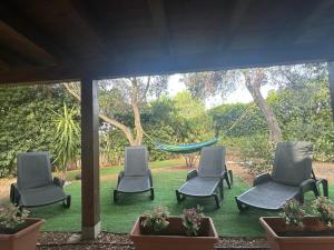 a group of chairs and a hammock in a yard at Villetta il caminetto in Geremèas +11 photos
