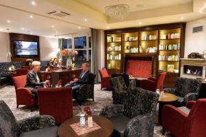a lobby of a hotel with two men sitting in chairs at Kurhotel Grüttner mit eigenem Sole Thermal Schwimmbad 32 Grad und Saunalandschaft in Erwitte
