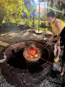 a woman is cooking over an outdoor grill at Family Room in Tam Kỳ