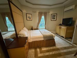 a bedroom with a bed and a tv and two windows at Richcastle Hotel in Freetown
