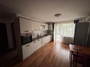 a kitchen with white cabinets and a wooden floor at Mio Apartments Silver in Cluj-Napoca