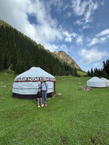 a woman and child standing in front of a yurt at Asiya in Karakol