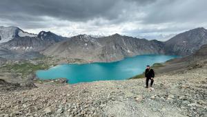 a man standing on top of a mountain overlooking a lake at Asiya in Karakol