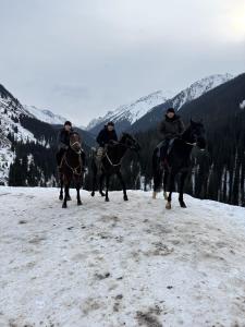 a group of four people riding horses in the snow at Asiya in Karakol