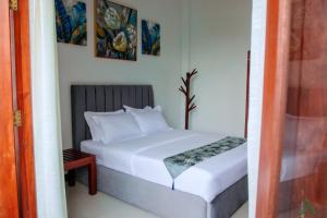 a bedroom with a white bed and some pictures on the wall at Harohi Hotel and Residence in Negombo