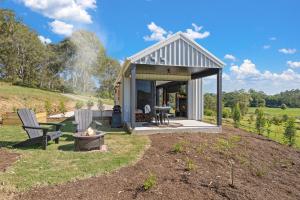 a small house on a hill with two chairs at Jinibara Cottage in Conondale