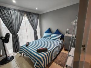 a bedroom with a bed with blue and white stripes at Sea la vie at Jbay in Jeffreys Bay