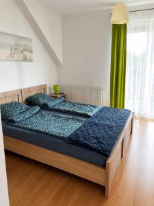 a bedroom with a bed with blue comforter at Pokoje na Brzozowej 2 in Białogóra