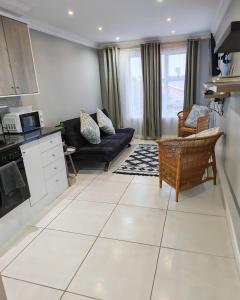 a kitchen and living room with a large white tile floor at Sea la vie at Jbay in Jeffreys Bay