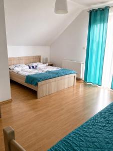a bedroom with a bed with blue curtains and wooden floors at Pokoje na Brzozowej 2 in Białogóra