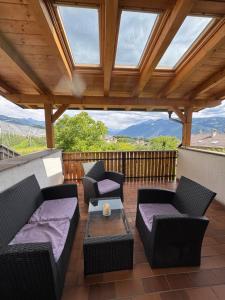 eine Terrasse mit Sofas und Stühlen und einem Holzdach in der Unterkunft Riedingerhof in Tisens