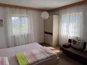 ein Schlafzimmer mit Bett, Sofa und Fenstern in der Unterkunft Riedingerhof in Tisens