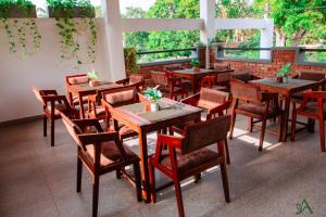 a restaurant with wooden tables and chairs and windows at Harohi Hotel and Residence in Negombo