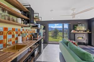 a kitchen and living room with a couch and a fireplace at Jinibara Cottage in Conondale