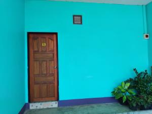 a blue wall with a wooden door in front at Saran Resort room 3 in Ban Khok Wat