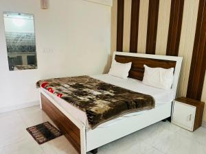 a bedroom with a white bed with a wooden headboard at Kaushalya River View in Solan