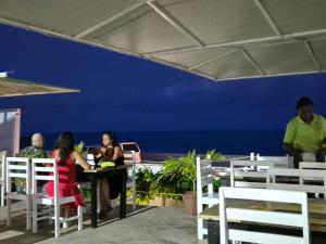 people sitting at a table with the ocean in the background at Hotel PZero in São Tomé