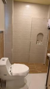 a white bathroom with a toilet and a shower at โรงแรม JP Lucky Lux Hotel in Ban Nong Samran