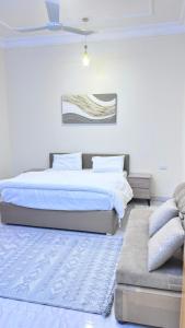 a white bedroom with a bed and a couch at شقق مفروشة الباحة in Al Baha